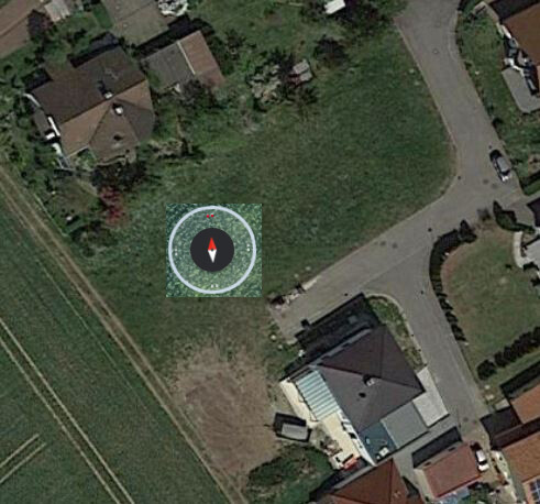 Luftbild eines Hauses mit Garten und Straße; Kompassmarker markiert Grundstückslage.