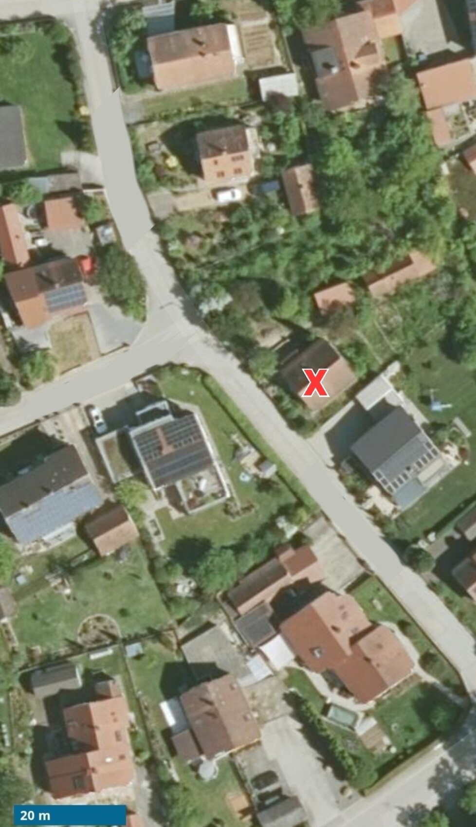 Luftbild eines Wohnviertels mit Straße, Gärten und Häusern, rotes X markiert ein Haus