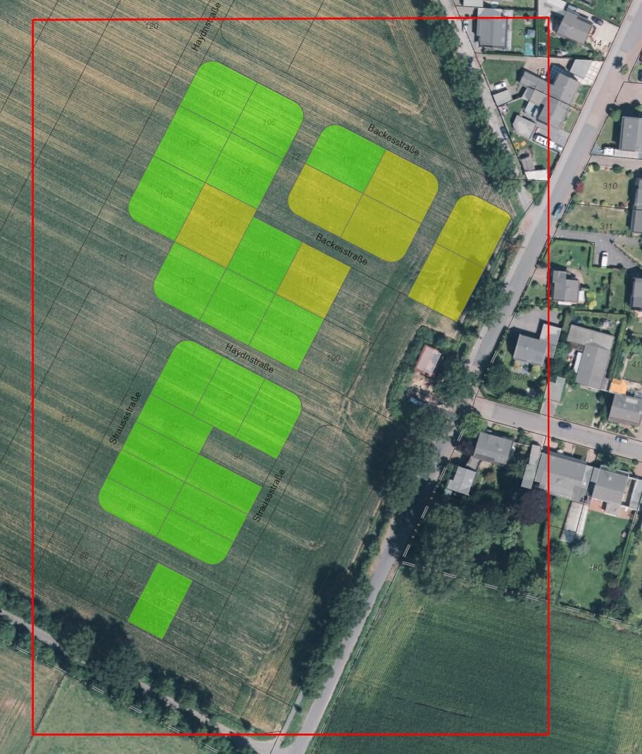 Luftbild: Grüne und gelbe Parzellen markiert auf Feldern neben Wohnhäusern.