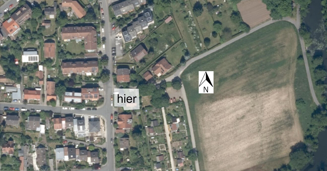 Satellitenbild eines Wohngebiets mit Feldern, Häusern und markierter Stelle hier