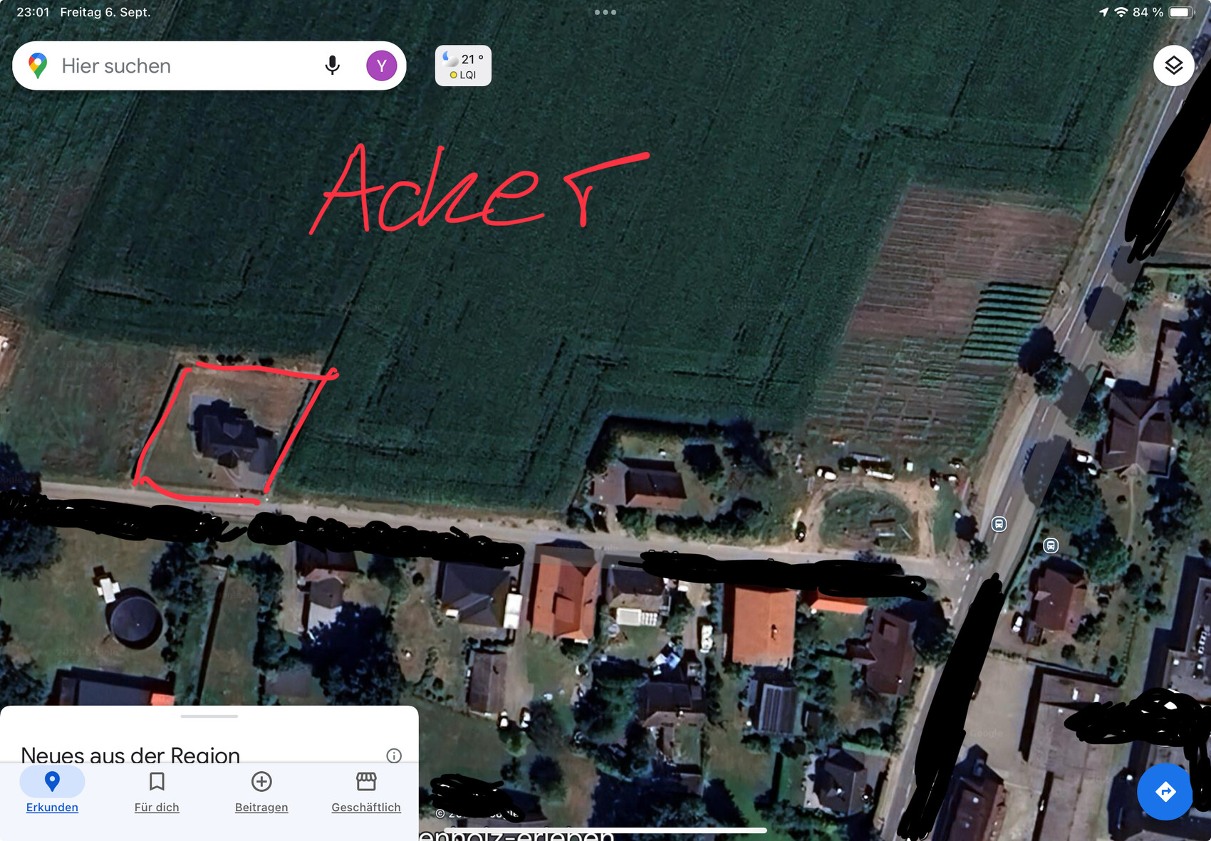 Satellitenbild eines Hauses am Straßenrand mit rotem Umriss des Grundstücks und Feldern dahinter.