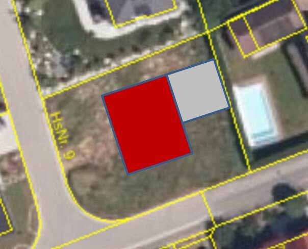 Luftbild: rotes quadratisches Gebäude, daneben graues Rechteck, gelbe Parzellenlinien.