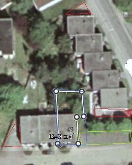 Luftaufnahme eines Gebäudekomplexes mit Grundstücksgrenze und Vermessungslinien.