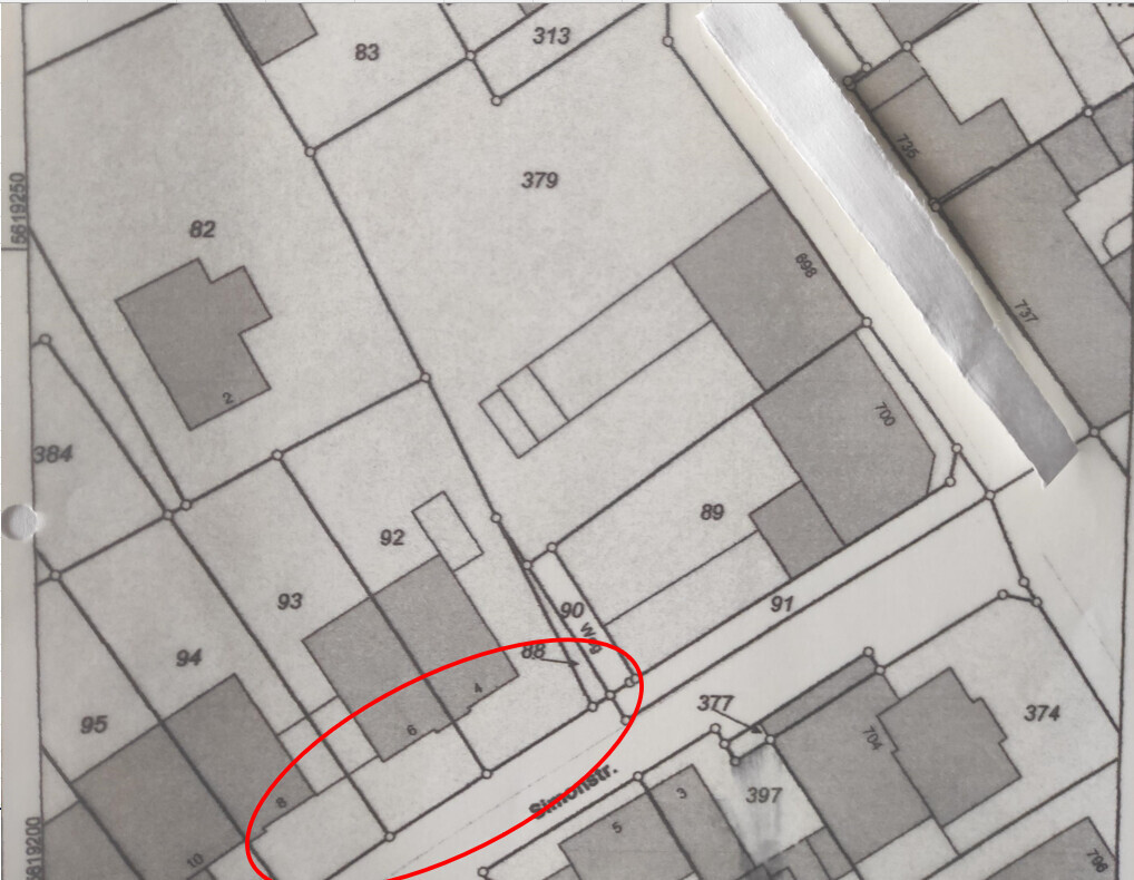 Lageplan mit nummerierten Grundstücken; roter Kreis markiert eine Parzelle neben einer Straße.