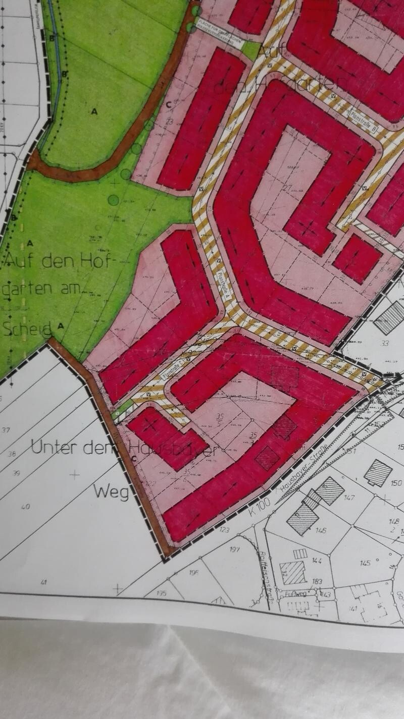 Stadtplan eines Wohnviertels: rote Gebäudeblöcke, grüner Park links, gelb gestreifte Straßen.