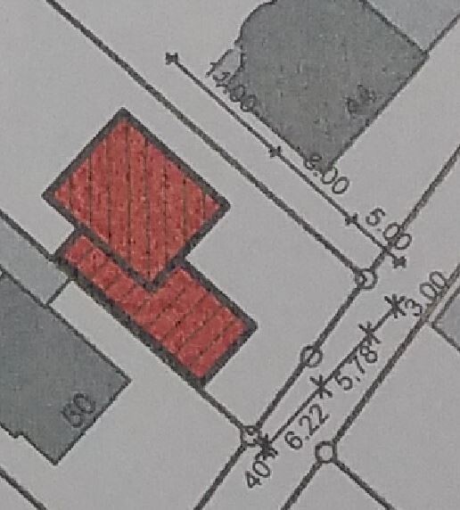 Lageplan eines Baugrundstücks mit rotem Gebäudegrundriss und Maßlinien