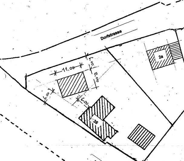 Lageplan eines Grundstücks entlang der Dorfstrasse mit drei schraffierten Gebäuden.