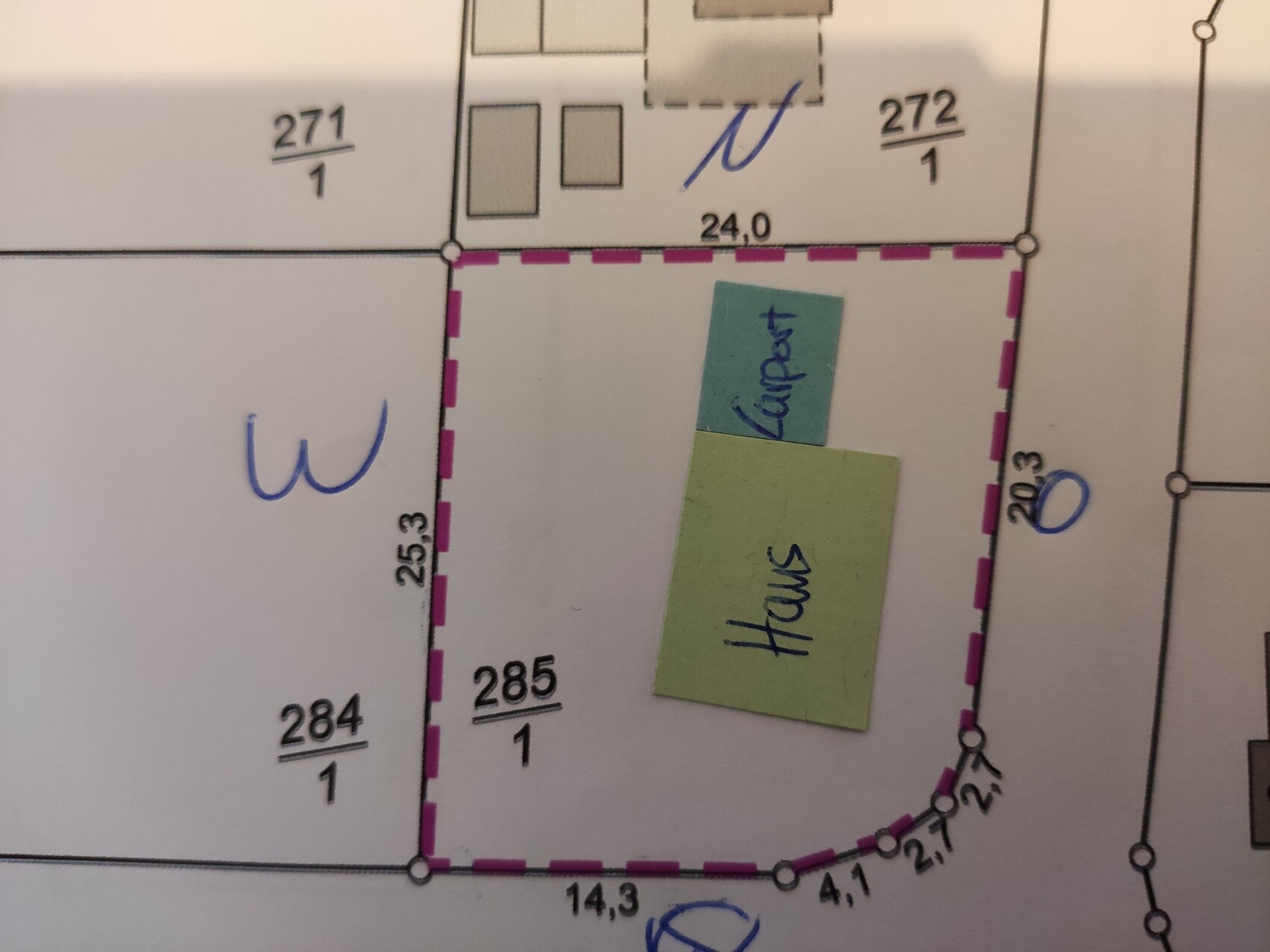 Lageplan eines Grundstücks mit pinkfarbener Umrandung; grüner Zettel 'Haus' und blauer Zettel daneben.