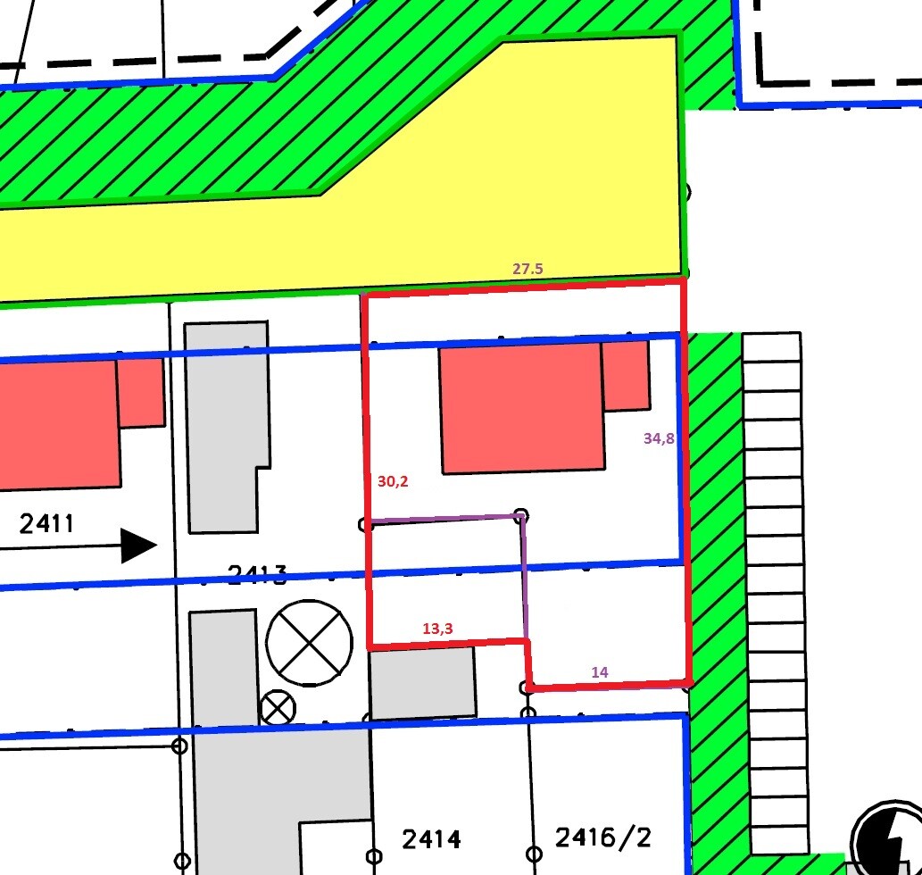 Lageplan: gelber Gebäudeteil, grün schraffierte Zone, rote Grundstücksgrenze, blaue Grenzlinien.