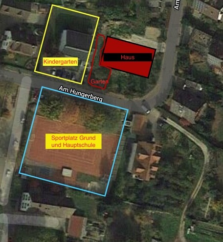 Luftbild eines Grundstücks mit Haus, Kindergarten, Garten und Sportplatz
