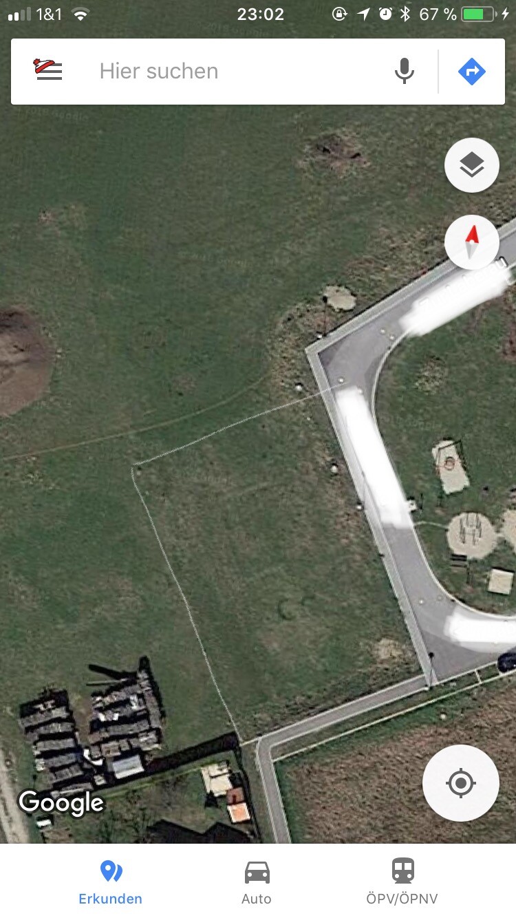 Satellitenansicht eines Baugrundstücks mit Zufahrtsweg und Grenzlinie
