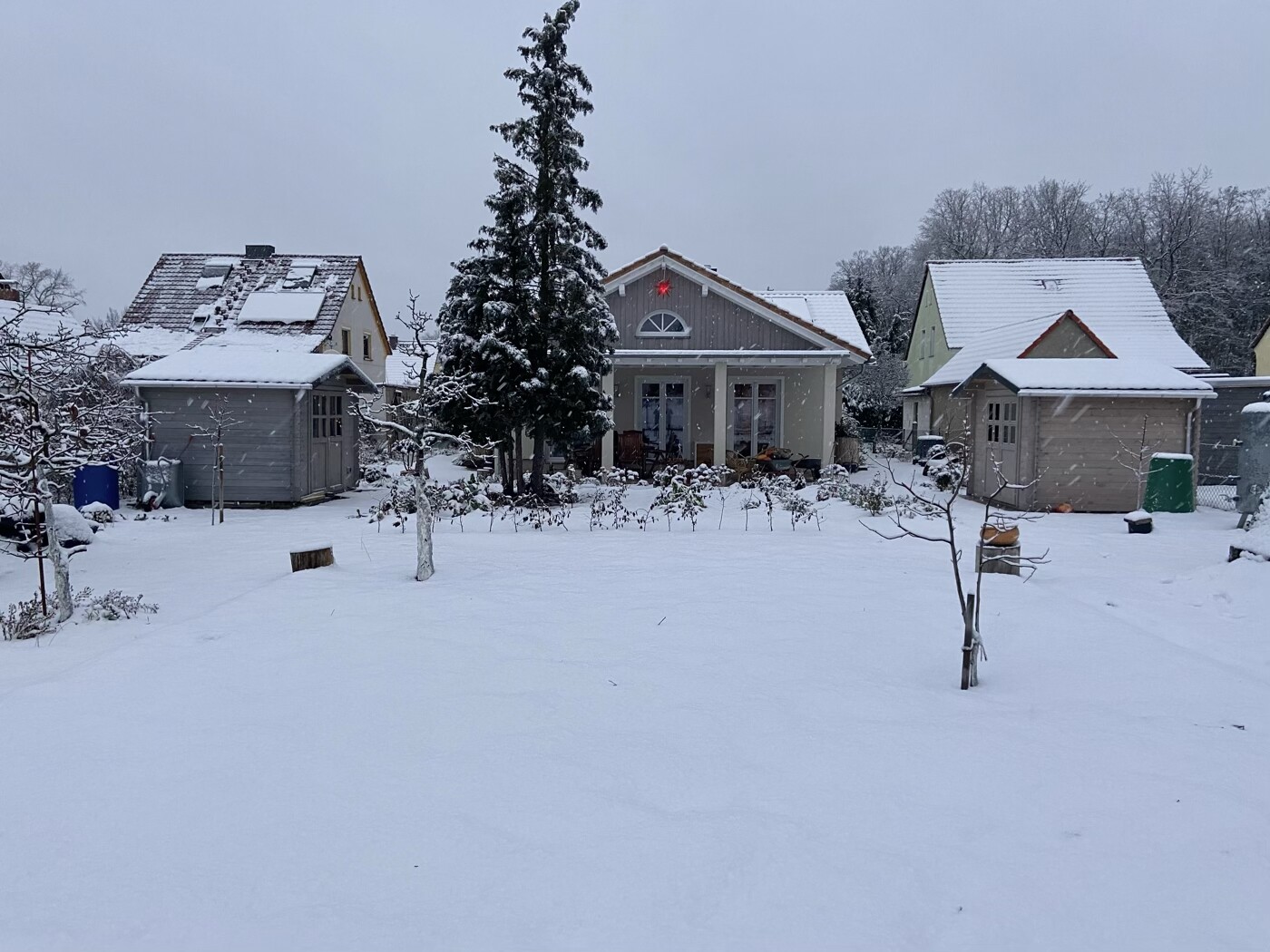 Schneebedeckter Garten mit Häusern, zentralem Wohnhaus und rotem Stern am Giebel.