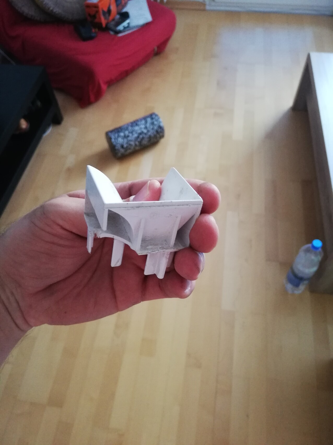 Hand hält kleines weißes 3D-gedrucktes Kunststoffbauteil im Innenraum