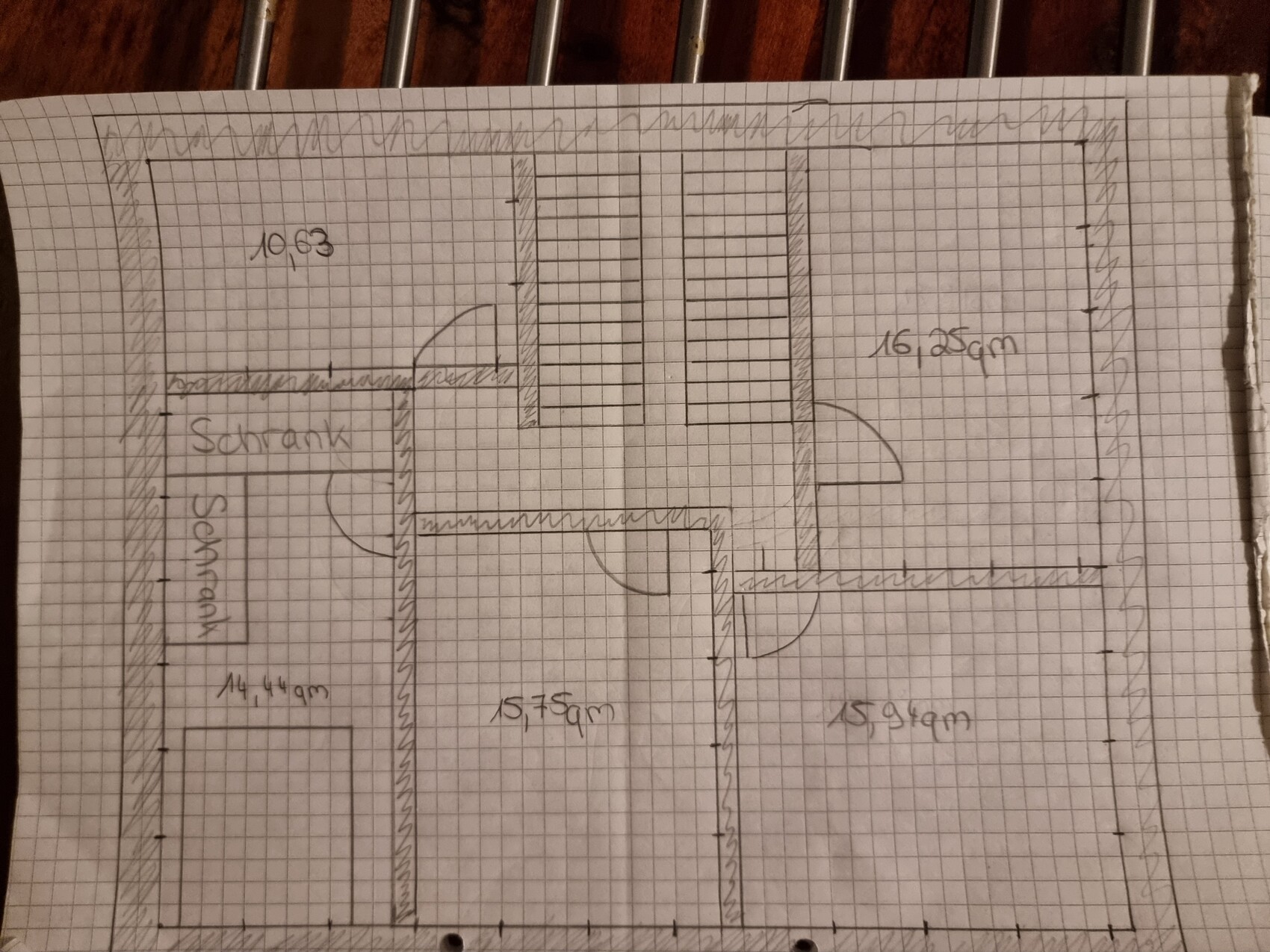 Handgezeichneter Grundrissplan auf Graphpapier, zeigt Räume mit Türen und Maßangaben.
