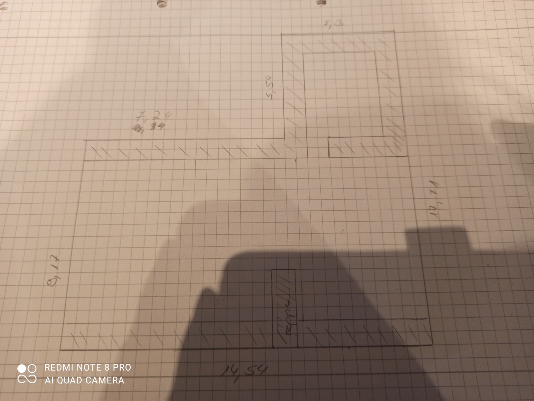 Handgezeichneter Grundriss auf Karopapier mit mehreren rechteckigen Räumen und schraffierten Wänden.