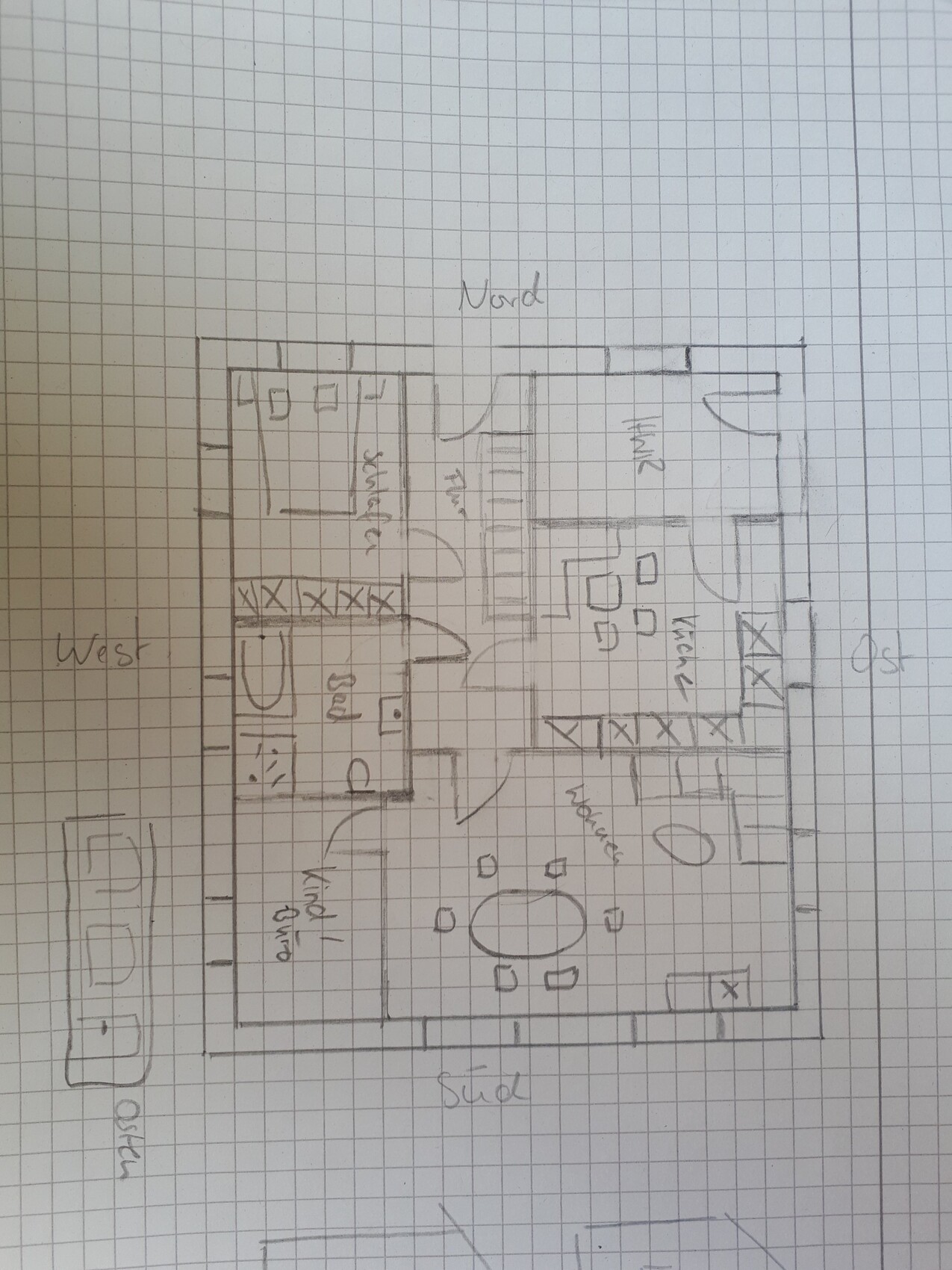 Handgezeichneter Grundriss eines Wohn- und Küchenbereichs mit Treppe auf kariertem Papier