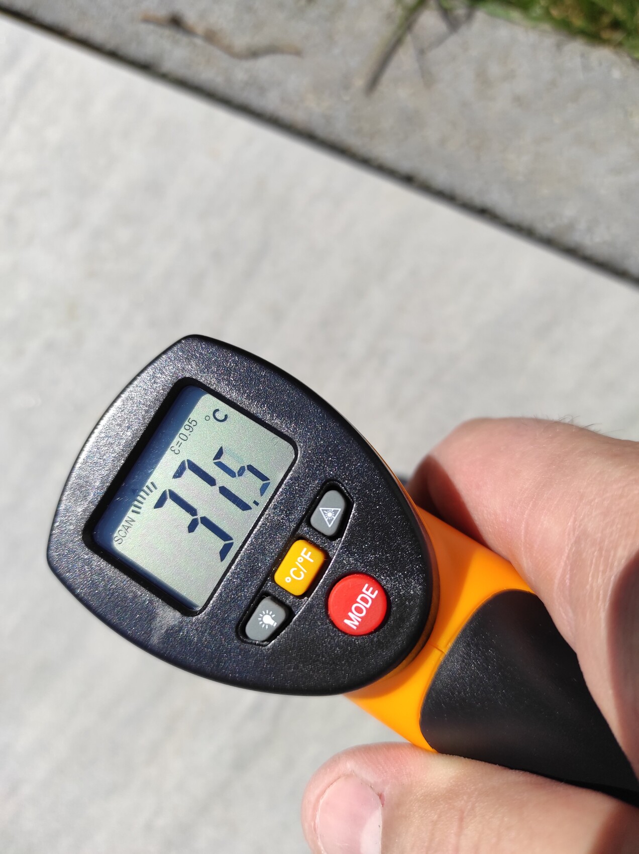Nahaufnahme eines orange-schwarzen Infrarot-Thermometers zeigt 27,7 °C von Hand gehalten.