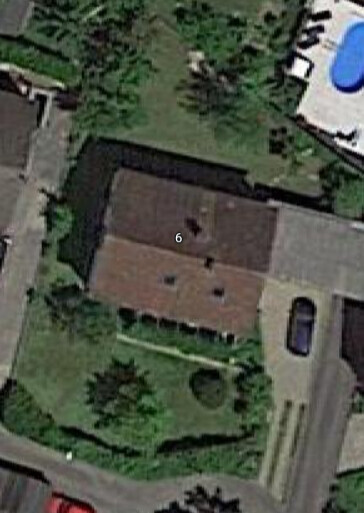 Vogelperspektive eines Einfamilienhauses mit Garten, Terrasse und Zufahrt.