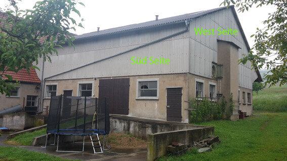 Großes Gebäude mit Betonunterbau, Metallseite, Trampolin im Garten; West- und Südseite beschriftet.