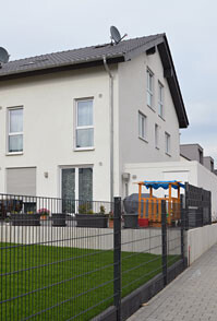 Außenansicht eines modernen Wohnhauses mit Gartenzaun und Spielgerät