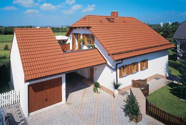 Weißes Haus mit rotem Ziegeldach, angeschlossene Garage, Einfahrt und Garten.