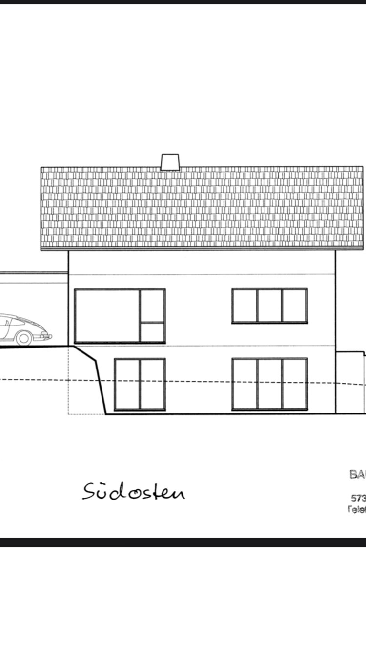 Zweistöckiges Haus mit Satteldach, großen Fenstern und Carport links, Südosten.