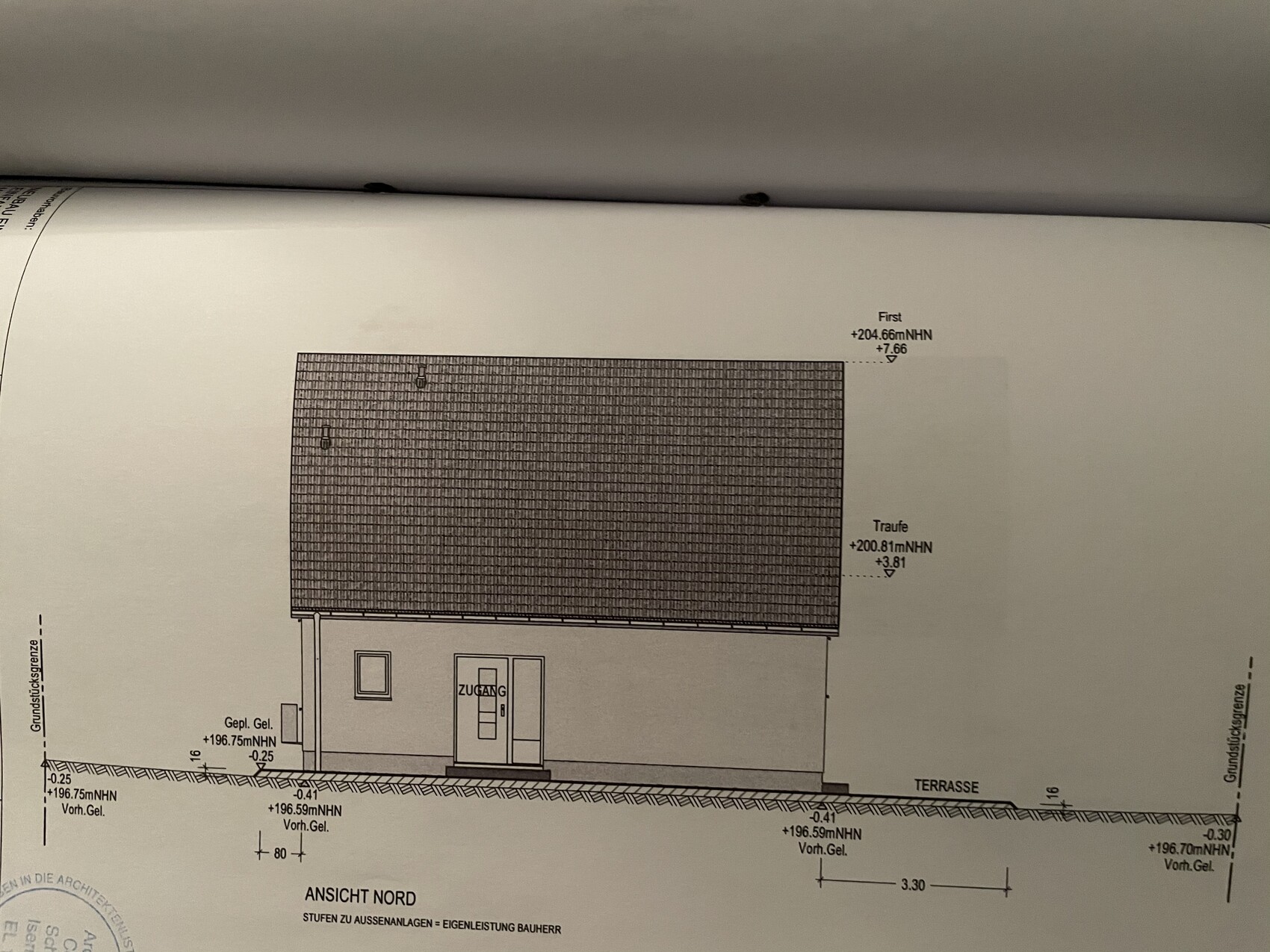 Nordansicht eines Einfamilienhauses mit großem Ziegeldach, Eingangstür Zugang und Terrasse.