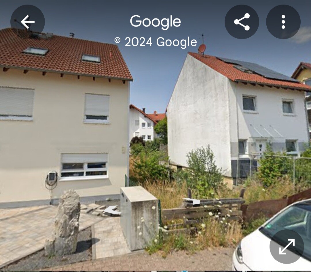 Zwei Häuser mit roten Dächern, beige und weiß, vorne Pkw, Garten und Zufahrt.