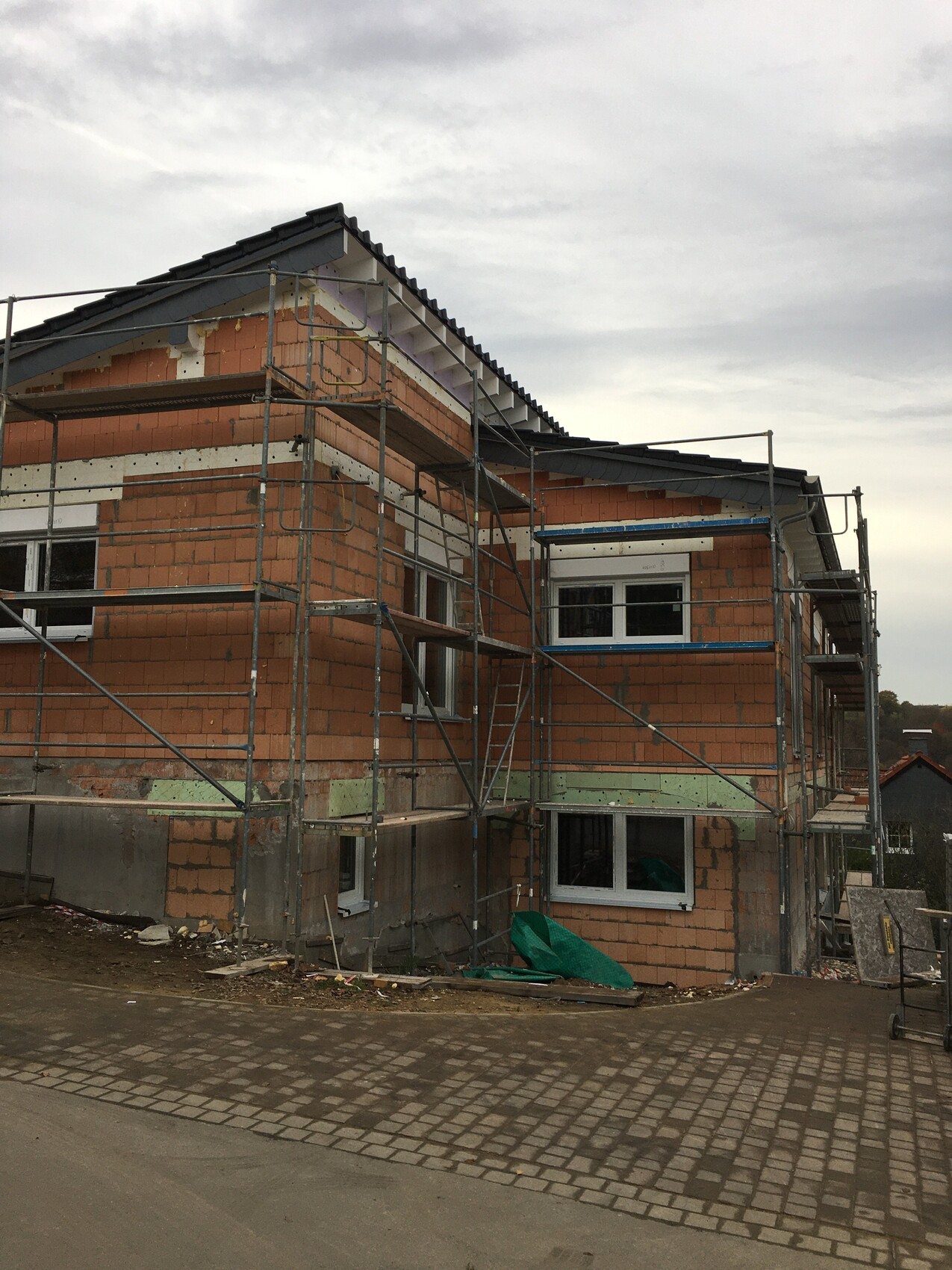 Rohbau eines mehrstöckigen Hauses mit Gerüst und orange Ziegelwänden