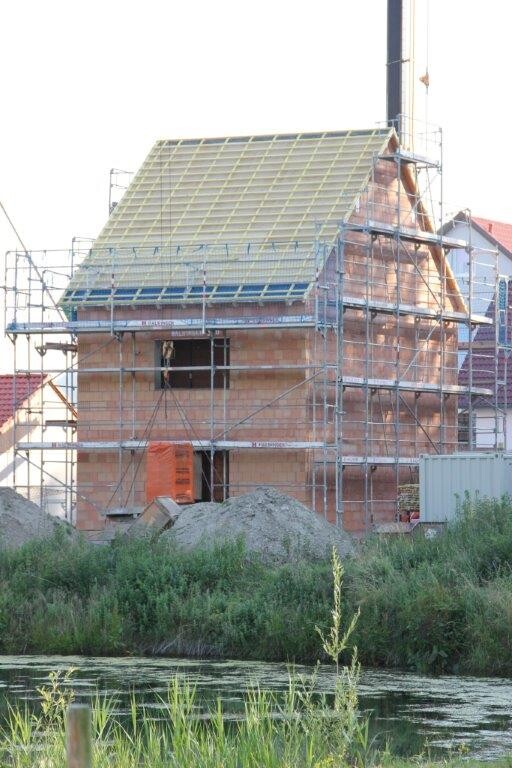 Hausbau Rohbau: Baustelle mit Gerüst, Ziegelwänden und unfertigem Dach