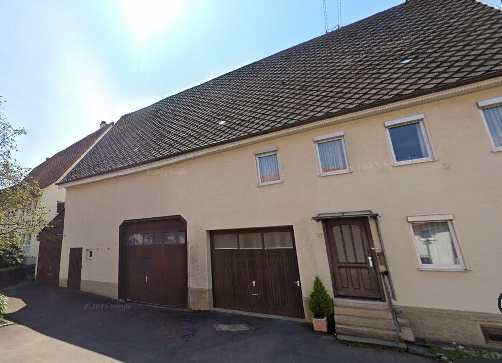 Straßenansicht eines zweistöckigen Reihenhauses mit zwei Garagen und Eingangstreppe