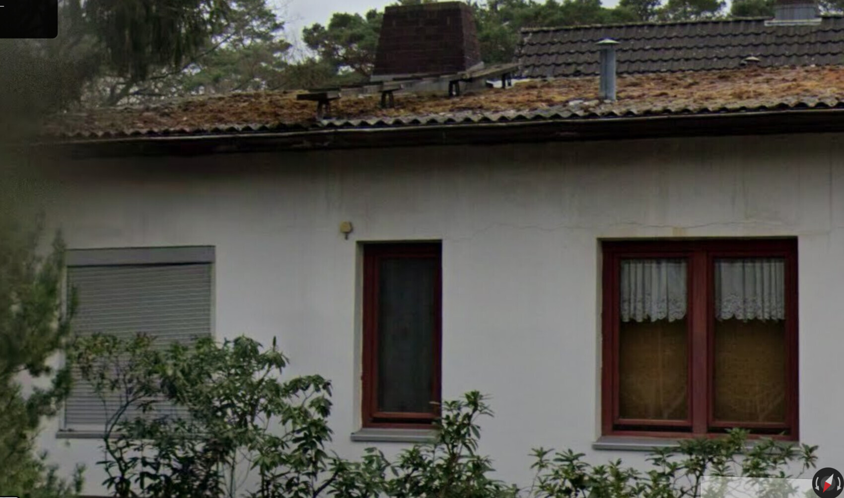 Außenansicht eines Hauses mit weißer Fassade, roten Fenstern und Dachziegeln