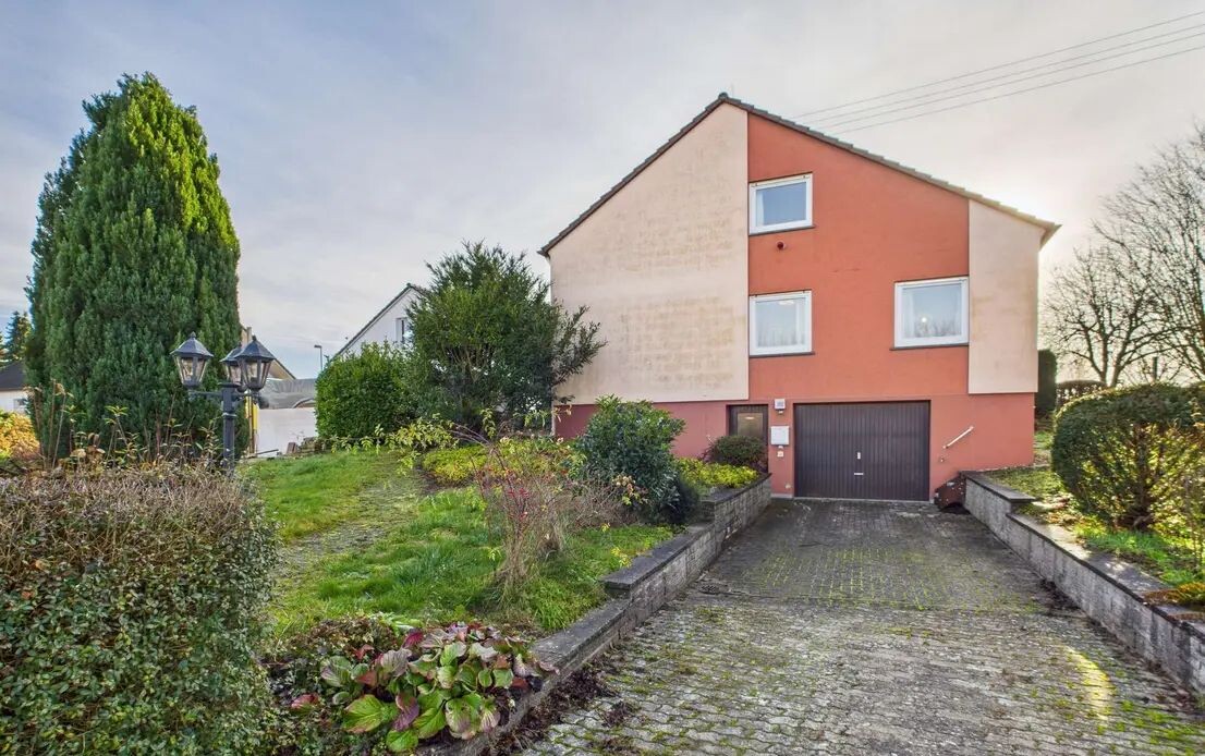 Vorderansicht eines zweistöckigen Wohnhauses mit Garage, Zufahrt und Garten