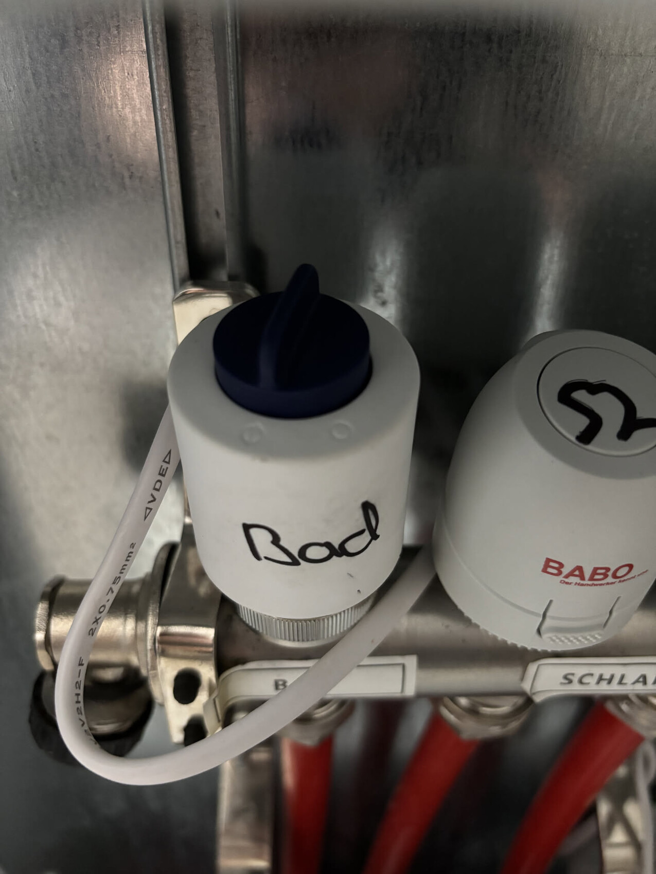 Nahaufnahme eines Absperrventils in der Haustechnik mit blauer Kappe und Metallrohren