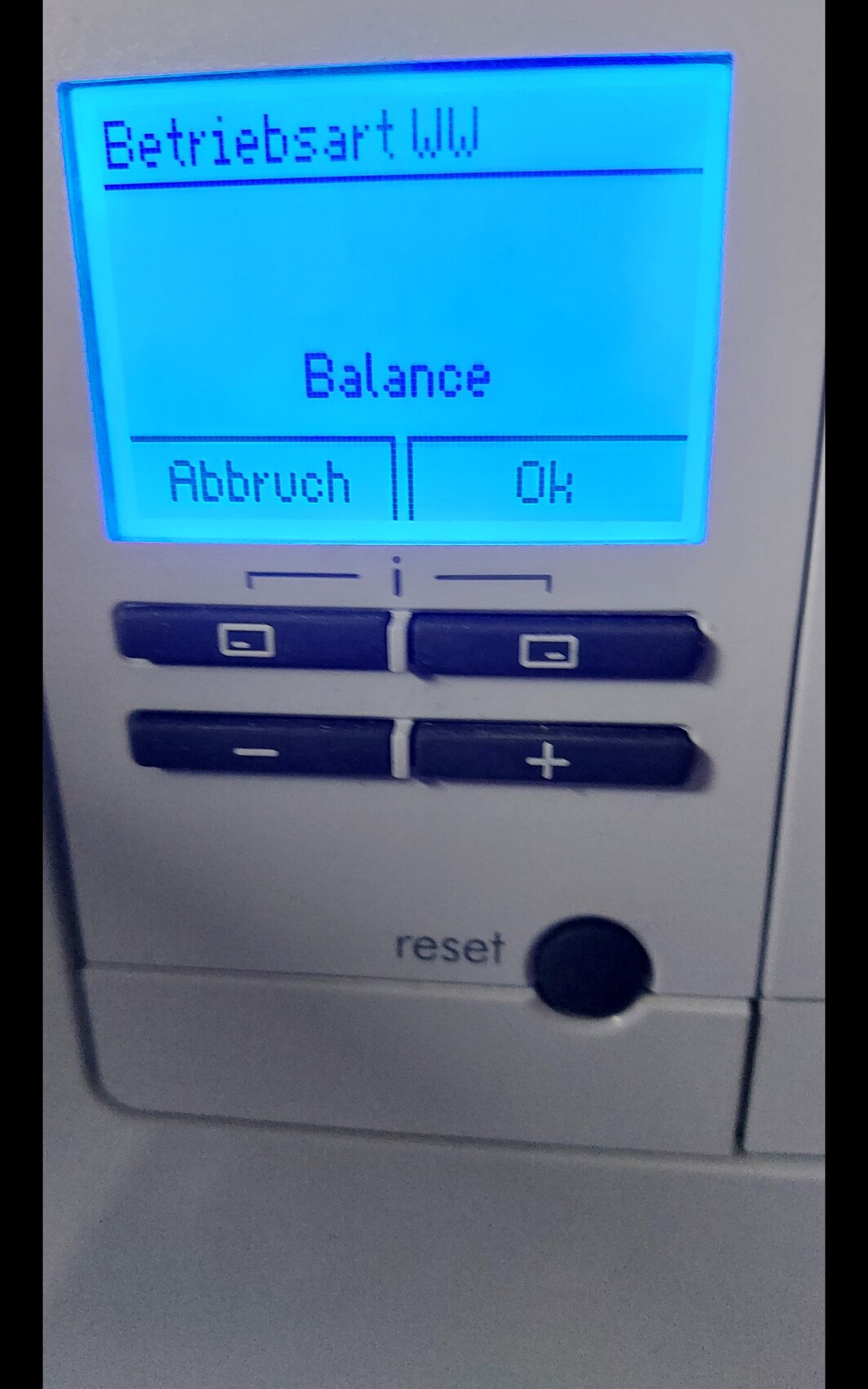 Blaues Display eines Geräts zeigt Balance mit Abbruch- und OK-Buttons; darunter Reset-Taste.
