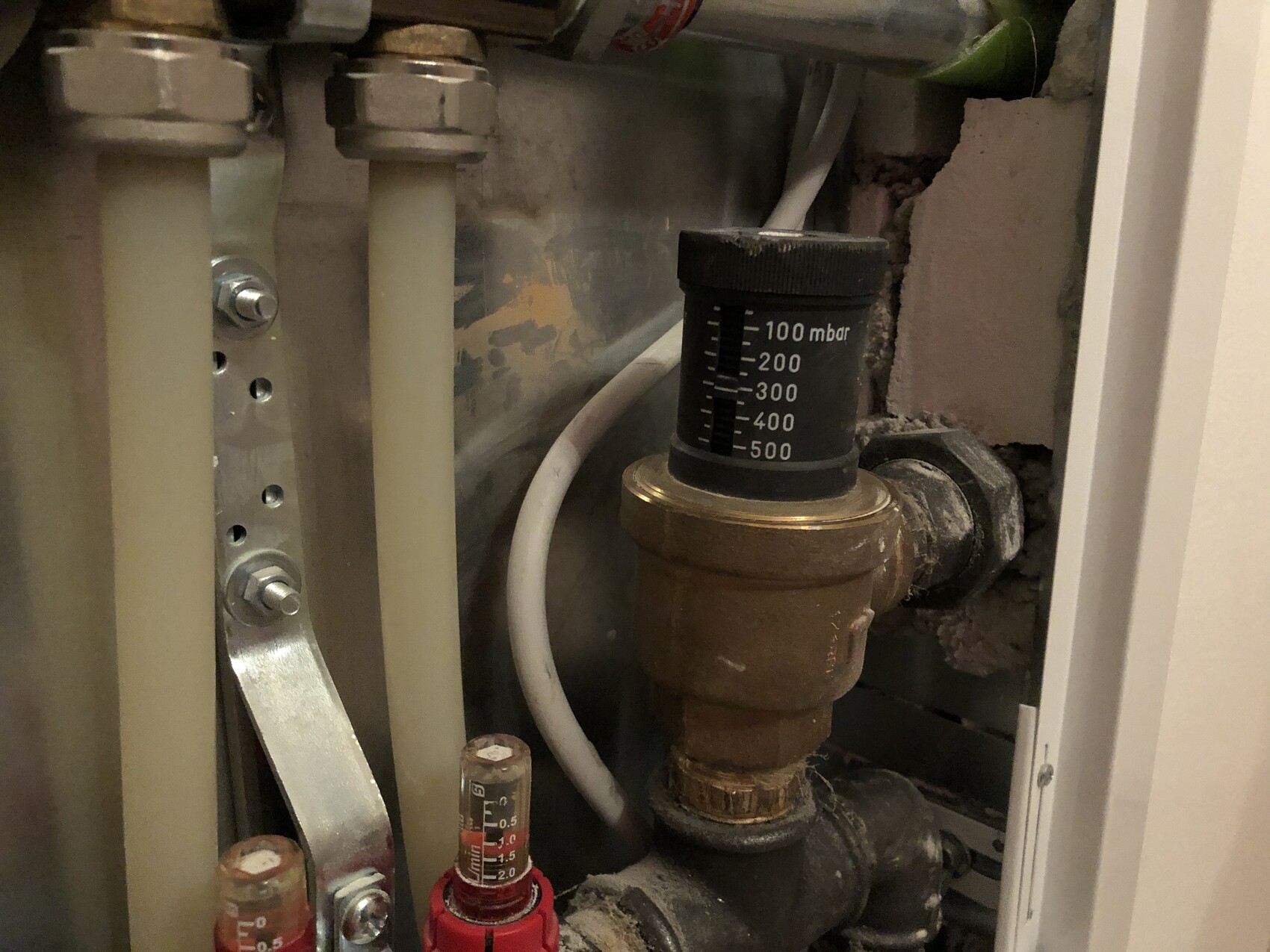 Nahaufnahme eines Druckreglers mit Skala 100–500 mbar in einer Heizungsanlage.