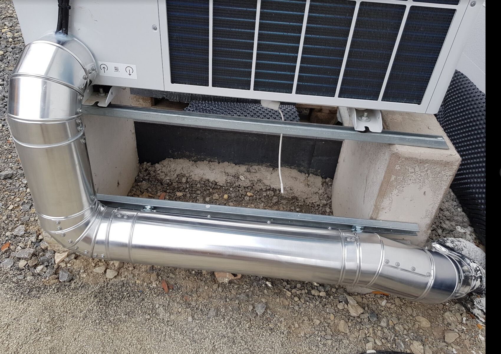 Außen-Einheit der Haustechnik mit Edelstahl-Luftkanal auf Betonfundament