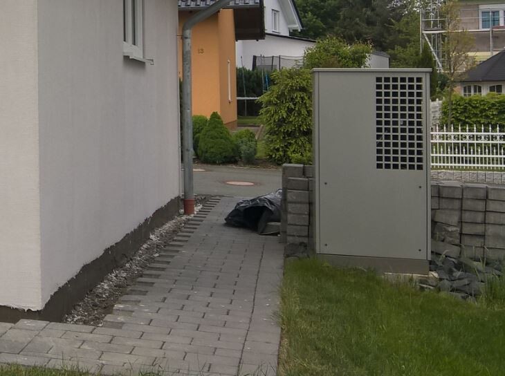 Gehweg neben Wohnhaus; rechts grauer Verteilkasten, davor schwarzer Müllsack.
