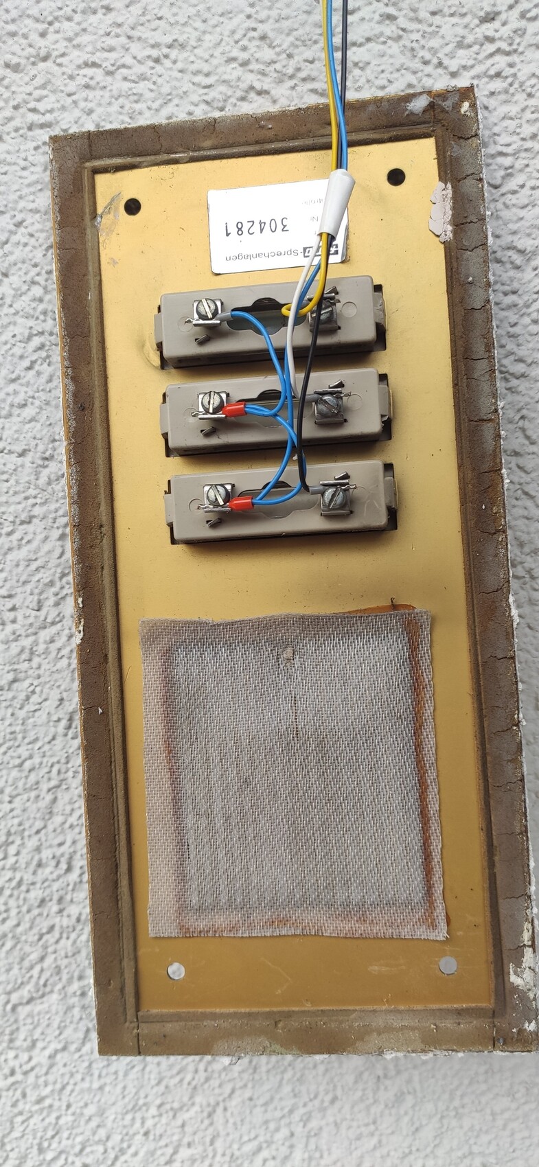 Wandmontiertes Elektrik-Panel mit vier Terminalblöcken, blauen und roten Drahtverbindungen.
