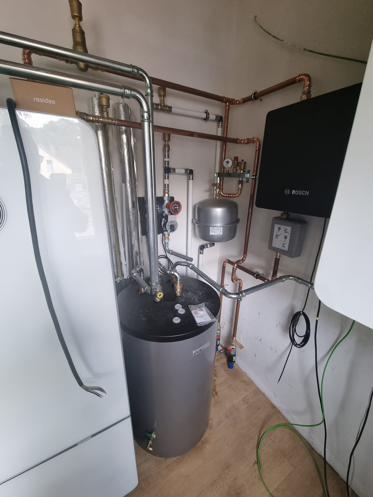 Heizungsraum mit Boiler, Warmwasserspeicher, Kupferrohren und Bosch-Steuergerät.