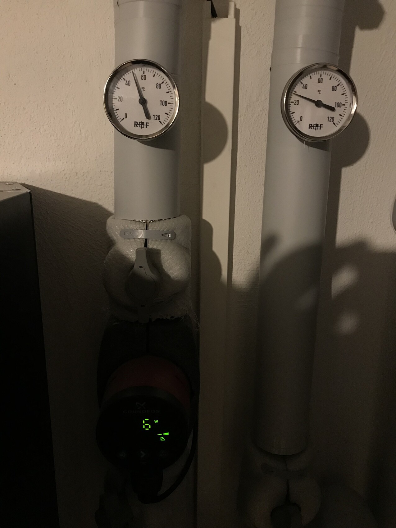 Zwei Druckmessgeräte an isolierten Heizungsrohren mit Thermostat unten