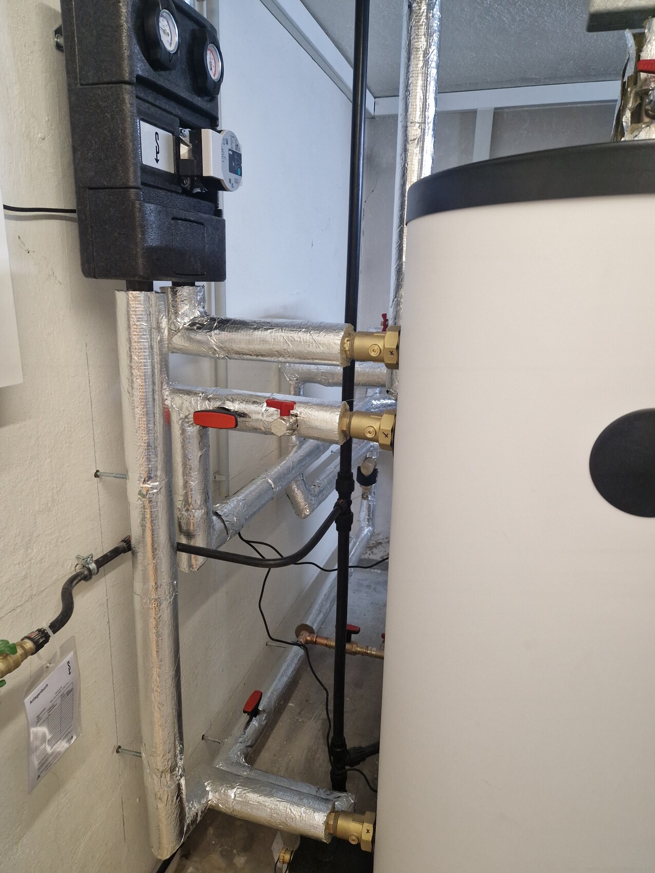 Heizungs- und Haustechnik im Technikraum mit isolierten Rohren und Absperrvorrichtungen
