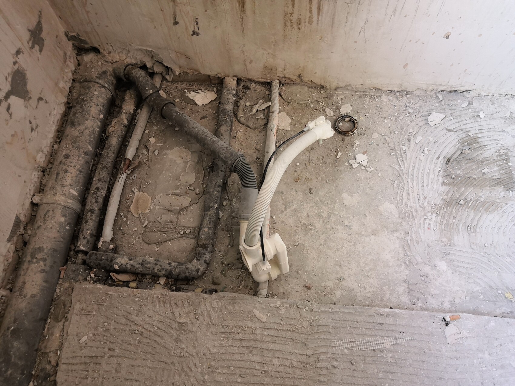 Bau-Rohbau mit Abwasserrohren, Installationsleitungen und Zementbodenbelag sichtbar