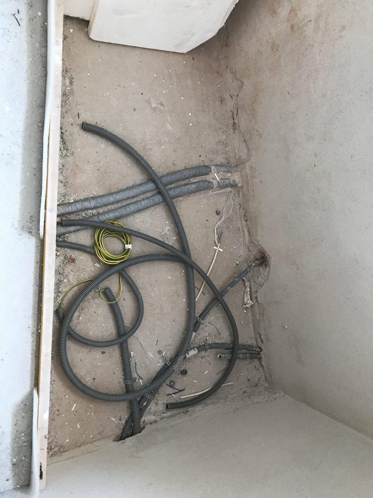 Rohbau Innenbereich mit Kabeln und Leitungen auf staubigem Boden
