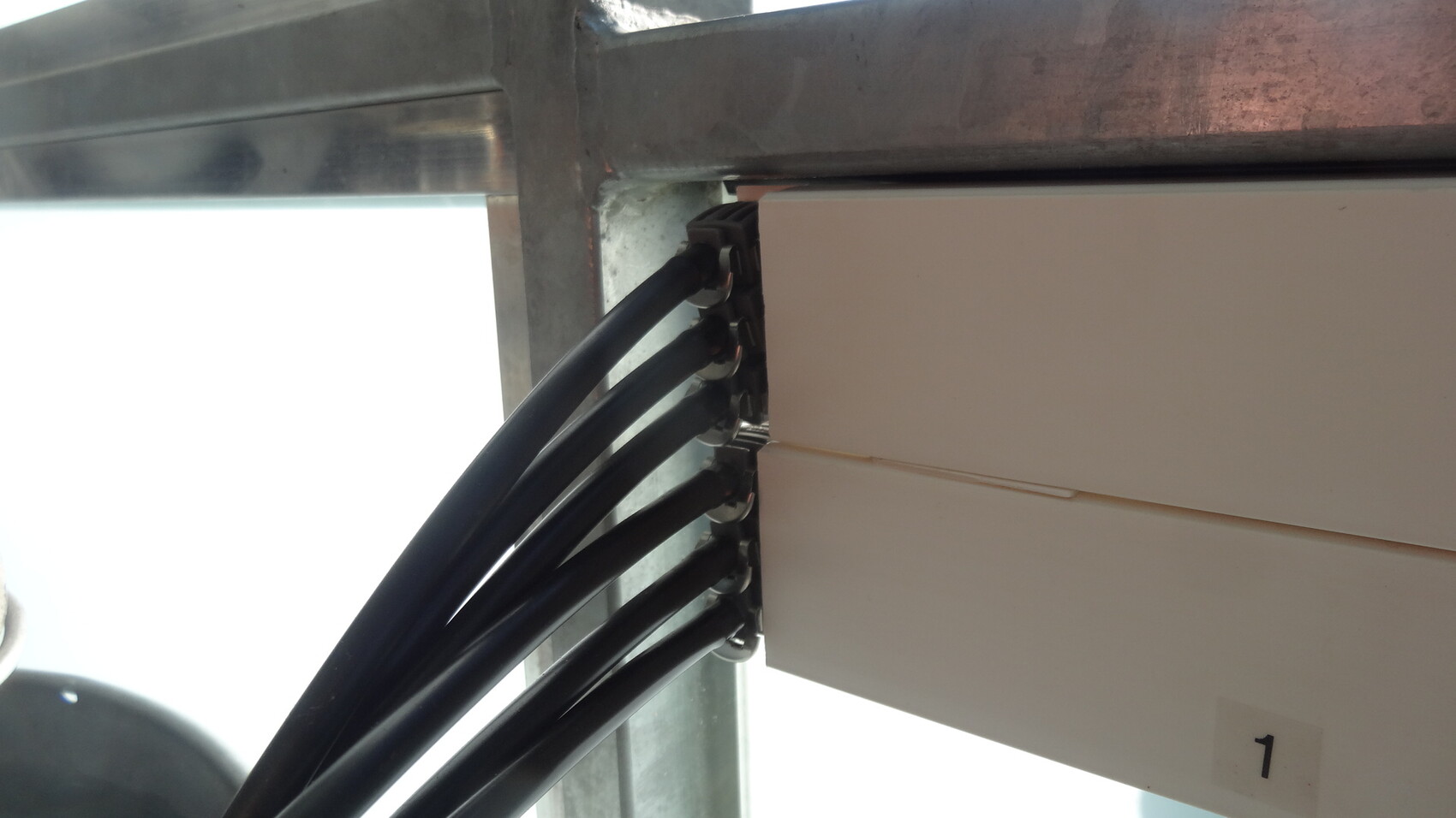 Mehrfachkabel führen zu einem Verteilerschrank in einem Stahlrahmen auf einer Baustelle
