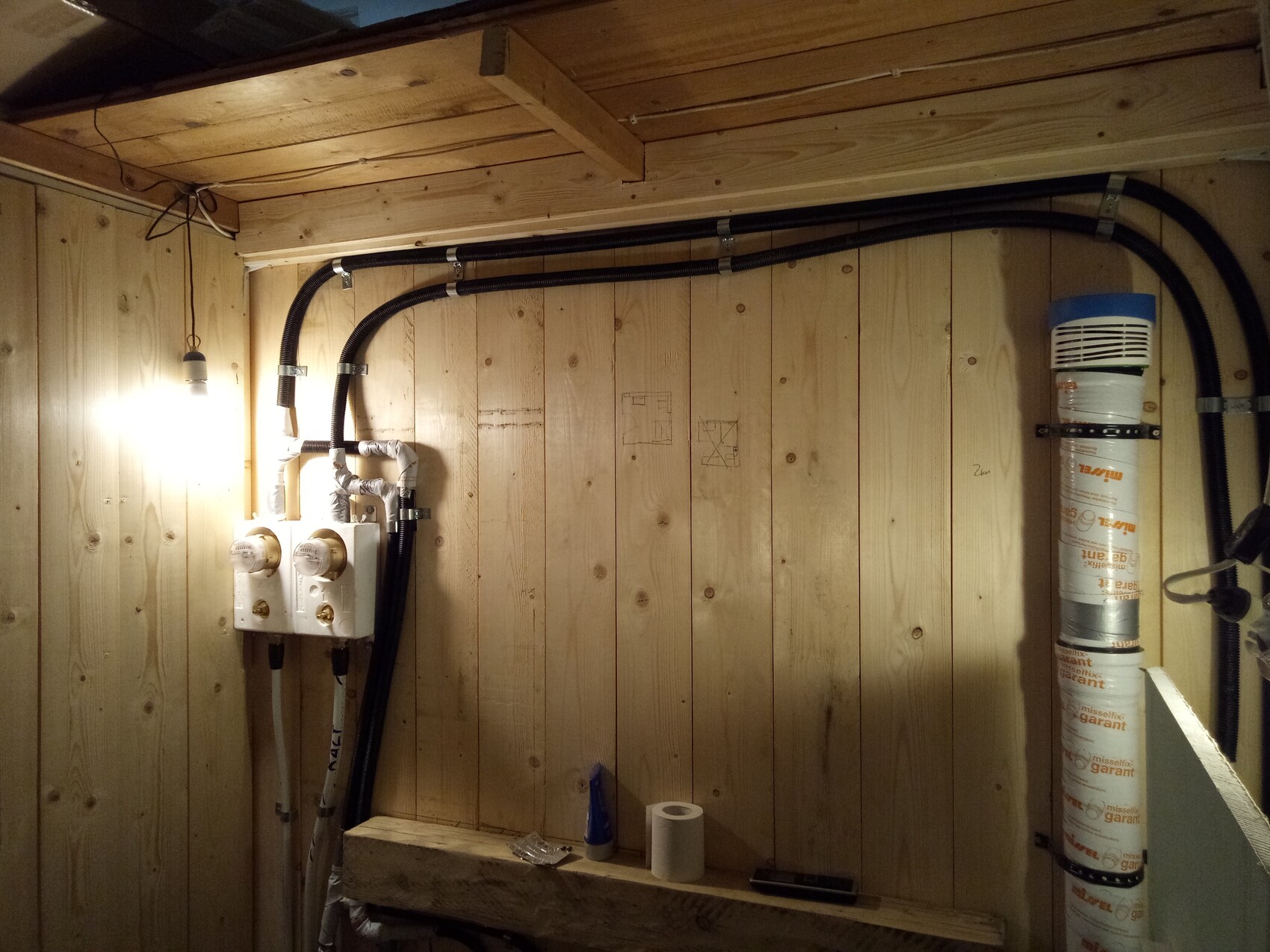 Kellerraum mit sichtbaren Wasserleitungen, Kabeln und Heizungsinstallation