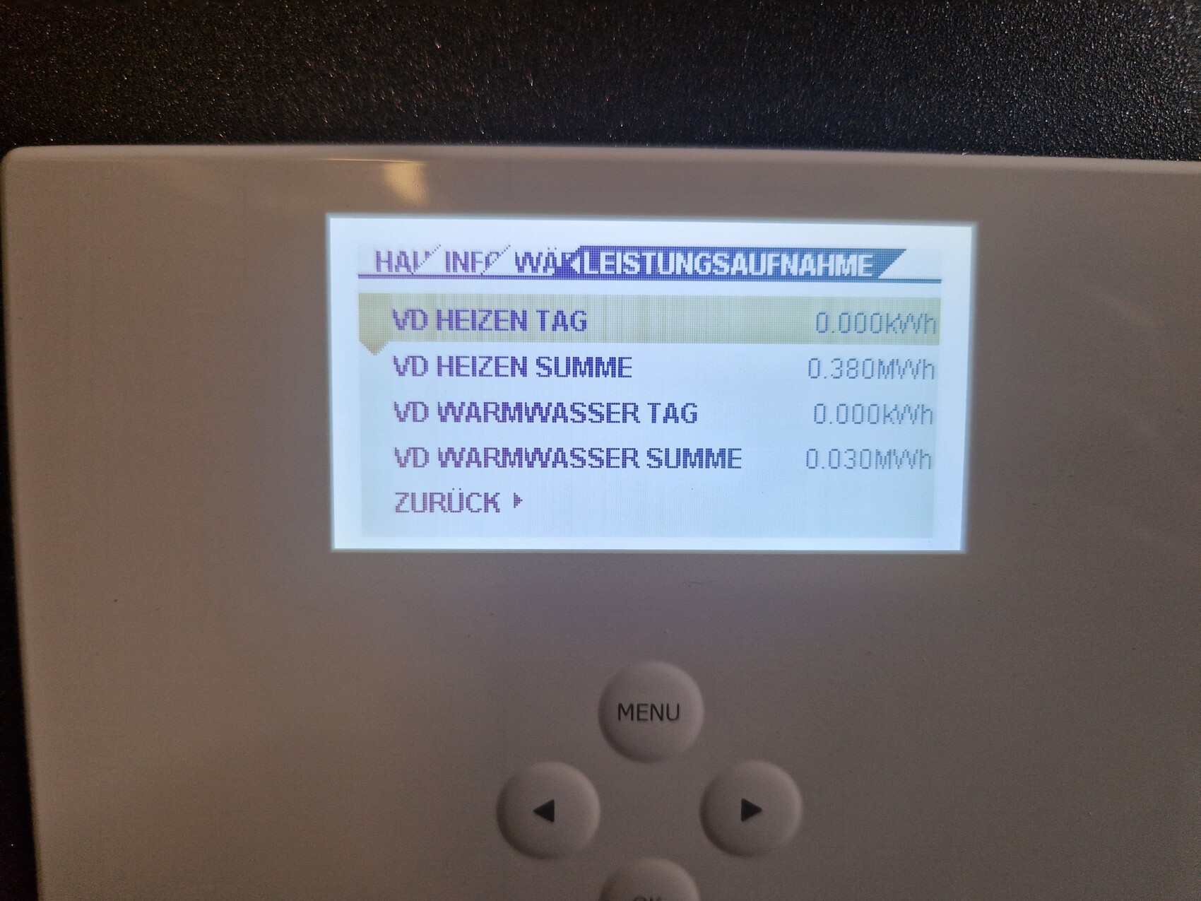 Kleines Display eines Energiemonitors zeigt Heiz- und Warmwasserwerte mit Menüknopf