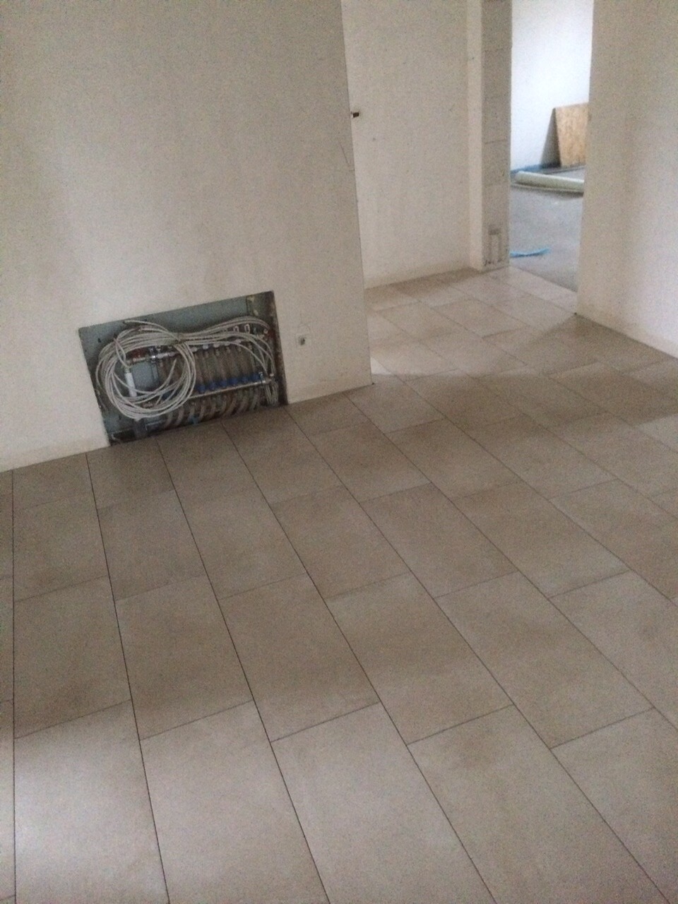Kabelverteilerkasten in der Wand mit aufgewickelten Kabeln; Fliesenboden.