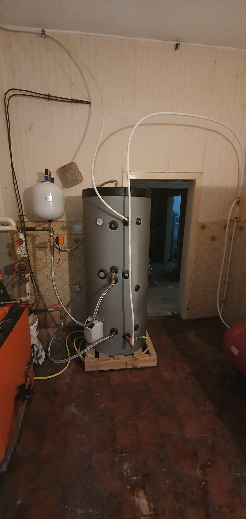 Großer zylindrischer Warmwasserspeicher mit Rohren und Druckanzeigen im Keller.