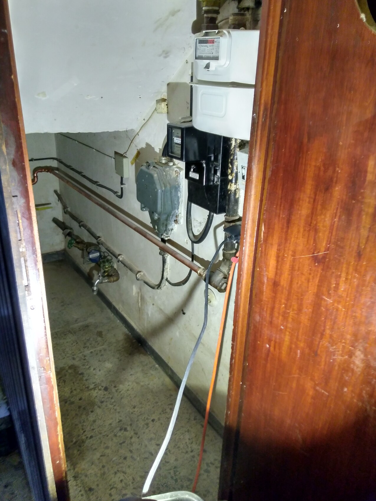 Kellerraum mit Gas- und Stromzähler, Rohren und Verkabelung an der Wand
